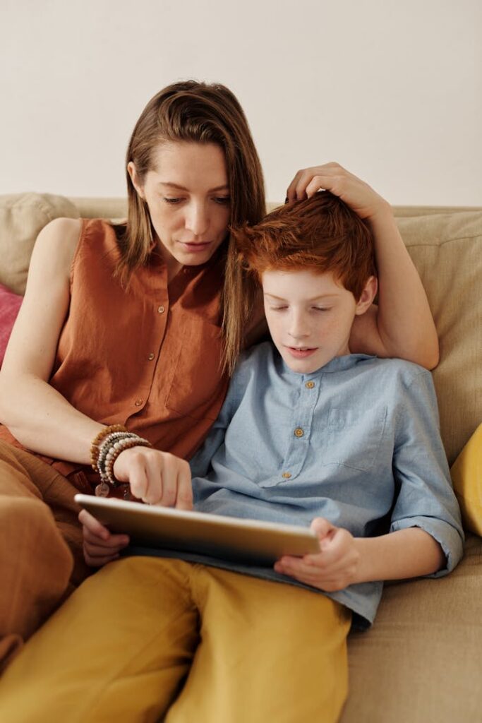 A mother and son bonding as they use a tablet together indoors.